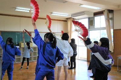 写真:小歌踊の練習風景。女子児童・生徒が、右手を腰に当て、扇を持った左手を上に伸ばしています。