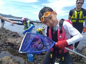 網に入った生き物を見せる男の子の写真