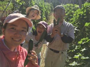 収穫した野菜をもって写真に写る3人のインターン制と生産者の男性の写真