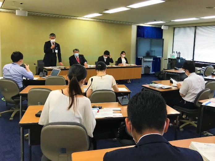 厚生労働省会見室で、記者を前にマイクを持って臨床研修医の海外留学制度の創設を発表している市長の写真