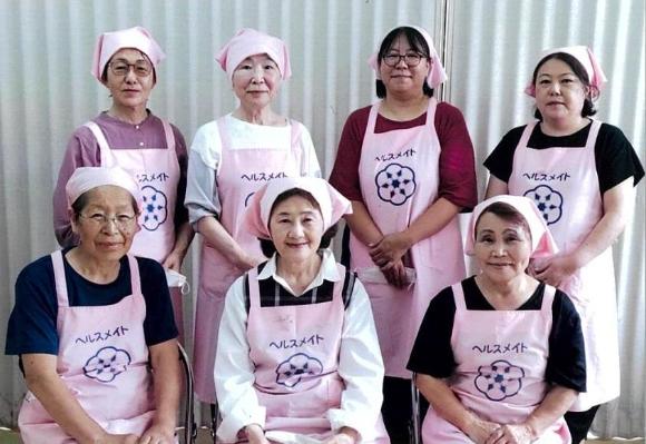 ピンクのエプロンをつけた比角地区の食生活改善推進員7人