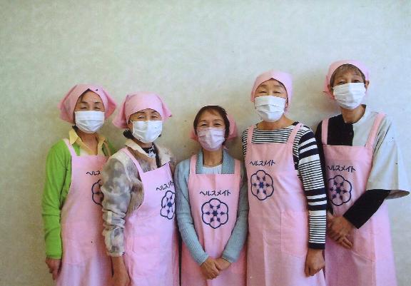 ピンクのエプロンをつけた一中地区の食生活改善推進員が5人並んでいる写真