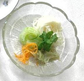 写真:涼しげなガラスの器に盛りつけられたそうめん。そうめんの上にはキュウリやニンジンなどが彩りよく盛られています。