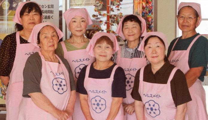ピンク色のエプロンと三角巾を着用した第二中学校地区の食生活改善推進員7名中3名が前方にあとの4名が後方に立って並んでいる写真。