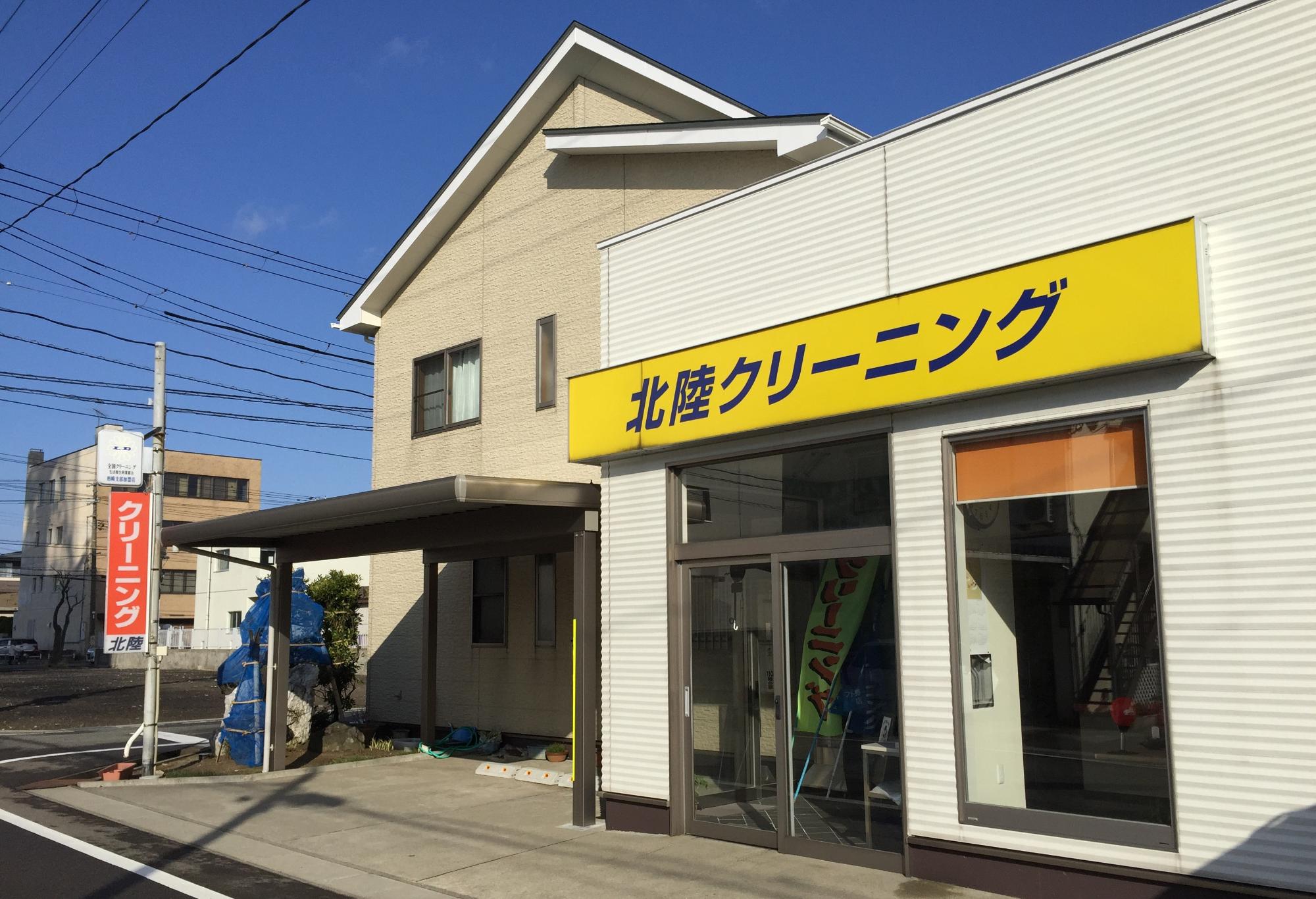 写真:お店の外観。入口上部に「北陸クリーニング」の黄色い看板がかかっています
