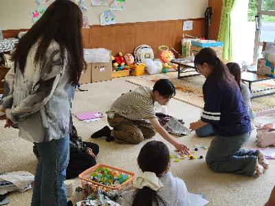 写真:ペットボトルのふたを使ったオリジナルの遊びを考えている学生たち。