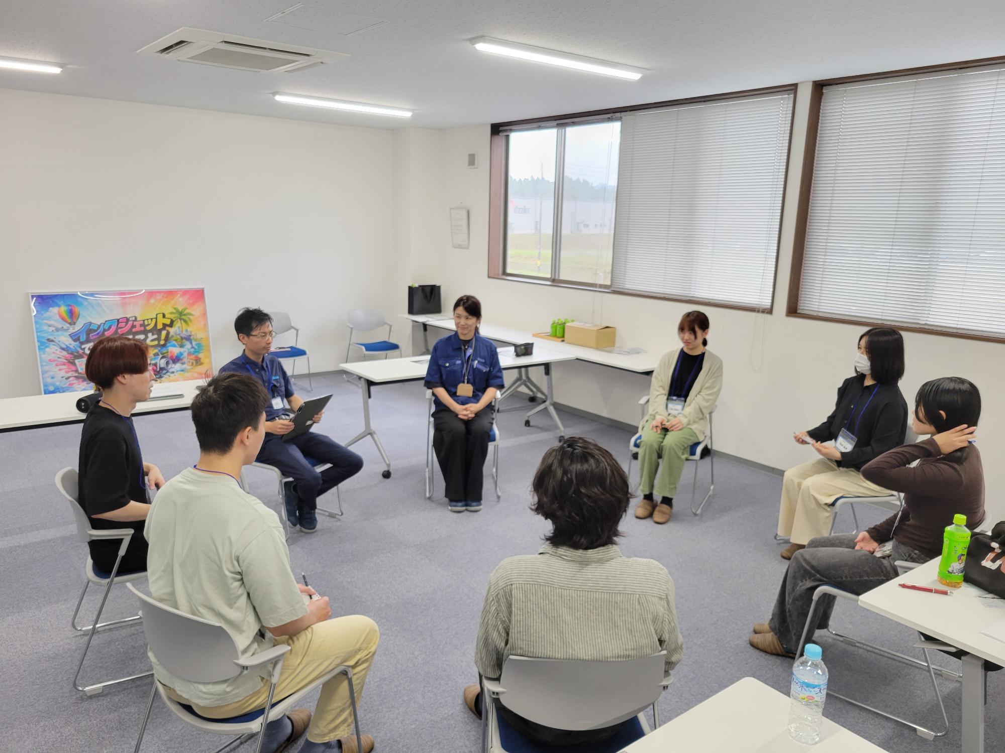 写真:社長、社員にインタビューを行う学生たち。お互いの顔をが見えやすいように、椅子が丸く並んでいます。