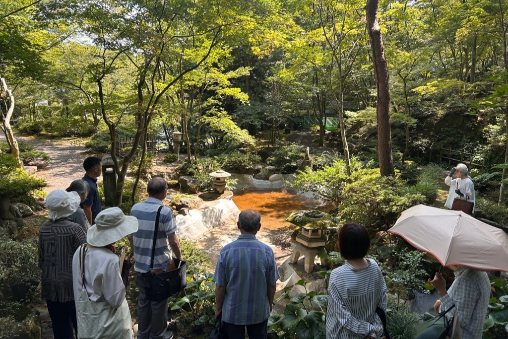 写真:ボランティアガイドが松雲山荘内の池を紹介している様子