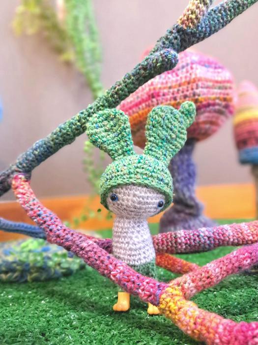 写真:緑の帽子を被った小さい編みぐるみの人形があります