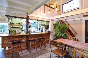 イーリーカフェの店内の様子です。木材を使用したテーブルとイスがあります。奥には厨房があります。厨房の前はカウンターになっていて、椅子が3脚並んでいます。窓から光が射しこむ明るい店内です。