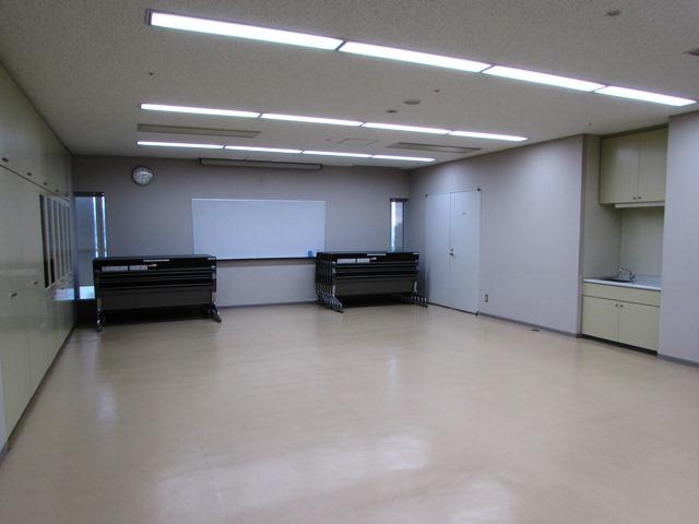 左側の壁には収納棚、正面の壁にはホワイトボード、右側の壁には小さな水盤が備えてある部屋の写真
