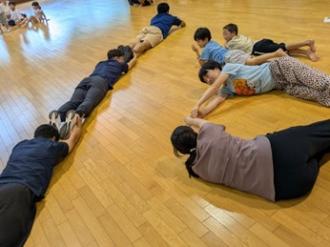 写真:7人で全身を使って数字の18を表現する様子