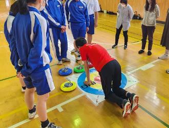 写真:カロ―リングの的の周りに集まりスポーツ推進委員が得点のつけ方を教えている様子です