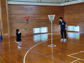 写真:女の子がスタッフの投げたボールを両手でキャッチしようとしています