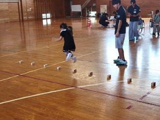 写真:参加者が床に置かれた積み木を踏まないように連続で跳んでいます