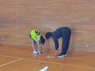 写真:参加者とスタッフが体前屈をしています。参加者はしっかりと床にてのひらがついています