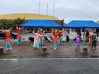 写真:よさこいチーム祭や倶楽部が踊りで応援している様子。オレンジの衣装を着ています