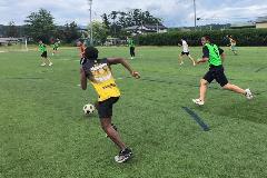 写真:マレーシア選手と新潟産業大学付属高校の生徒グラウンドでサッカーをしています