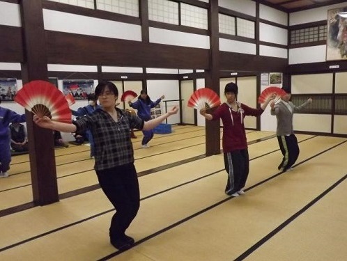 小歌踊の練習をする3人の女性が手に赤と白の扇子持って踊りの練習している様子の写真