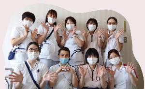 写真:9人のスタッフが笑顔で両手を広げています