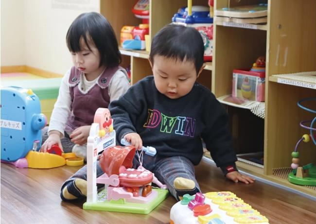 写真:ジャングルキッズ備え付けのおもちゃで遊ぶ男児と女児。後ろの棚にもたくさんのおもちゃがしまわれています。