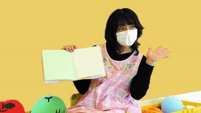 写真:絵本の読み聞かせをするともみ先生。右手で絵本を広げて見せています。
