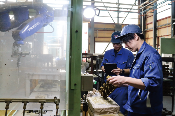 写真:2人の男性が工場内で出来上がった金型をタブレットで確認しているところ