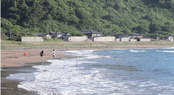 写真:穏やかな波が打ち寄せる砂浜で遊ぶ2人の子ども