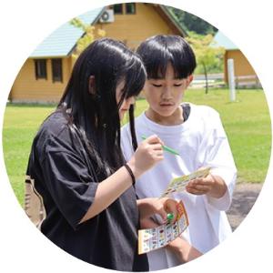 写真:ビンゴを楽しむ男の子と女の子。顔を突き合わせて相談しています