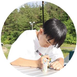 写真:鳥の鳴き声が出せる笛のようなものに絵付けをする男の子