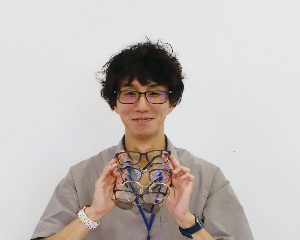 眼鏡をかけた男性の写真があります。手にはたくさんの眼鏡を持っています