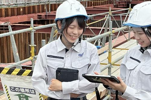 写真:鉄骨があらわになった現場で、同僚と現場確認中の橘さん