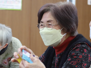 写真:出来上がった折り紙を前に微笑む女性参加者
