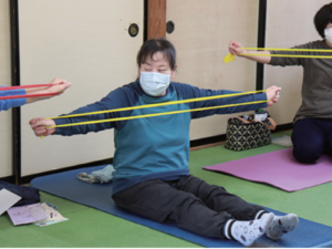 写真:ゴムバンドを胸の前で体操の参加者