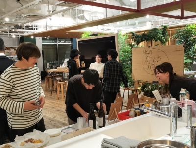 写真:料理が並ぶカウンターのそばで談笑する参加者とトークゲスト