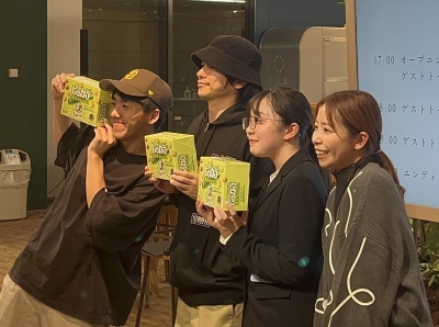 写真:萩野さんが開発したお菓子を持って記念撮影する参加者