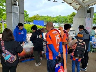 写真:ブース出展の様子。アルビレックスのユニフォームを着たサポーターがブースを覗いています
