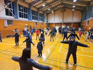 体育館で大勢の人が体操をする様子の写真