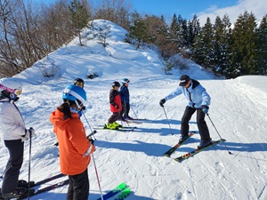 スキー場で講師からスキーを習う参加者の写真