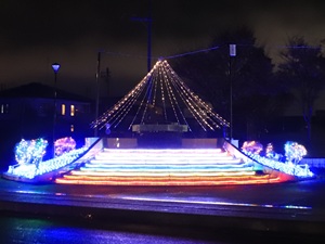 青やオレンジ色などにライトアップされた駅前公園の日時計の写真