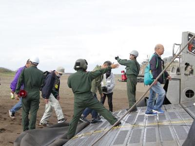 写真：砂浜に上陸した自衛隊のエアクッション艇に乗船する市民の皆さん。自衛隊員が誘導しています