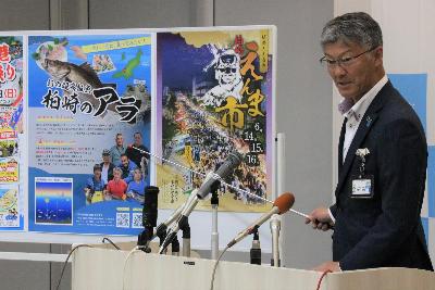 写真：高級魚アラのポスターを指しながら市長が説明をしています