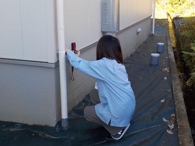 調査員が屋外で壁の幅を測る家屋調査の様子の写真