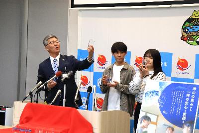 写真：市長とコップのデザイン等に携わった大学生が説明をしています。