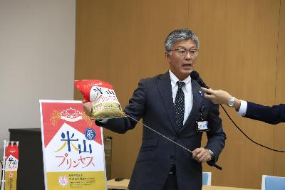 写真：市長が「米山プリンセス」の米袋を持って説明しています。