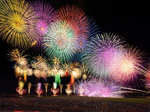 海から上がる色とりどりの花火の写真