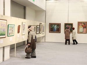 壁に掛けられた花の絵を見る人の写真