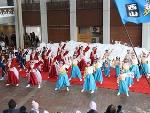 赤と青の衣装でよさこいを踊る様子の写真