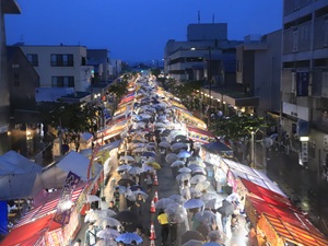 夜に屋台の間を行きかうたくさんの人の写真