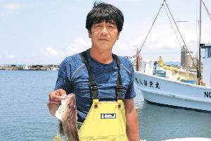写真：釣った魚を手に持つ茂田井さん